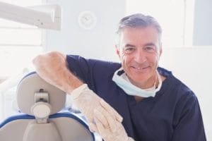 36421675 - улыбающийся стоматолог, прислонившись к креслу стоматолога в стоматологической клинике