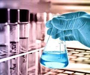 Nahaufnahme der Hand des Wissenschaftlers mit Gummihandschuh unter Verwendung von Chemikalien in einem Labor