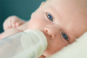 Foto de un bebé bebiendo de un biberón con agua del grifo fluorada