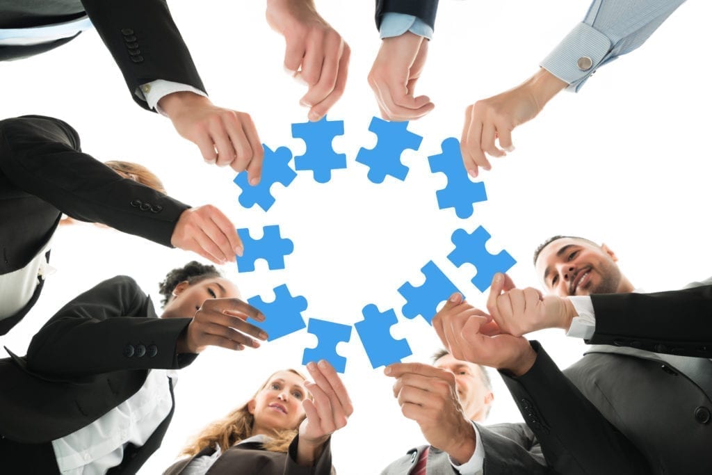 IAOMT Team Joining Puzzle Pieces In Huddle