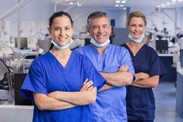 Велика група iaomt стоматологів та асистентів, що стоять у колі, даючи п’ятірку