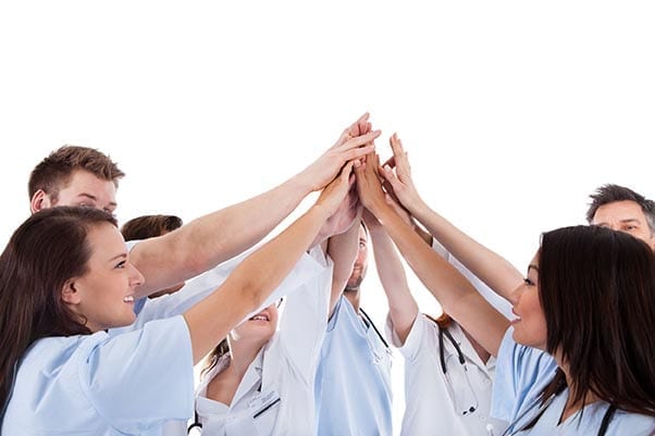 Large group of iaomt dentists and assistants standing in a circle giving a high five